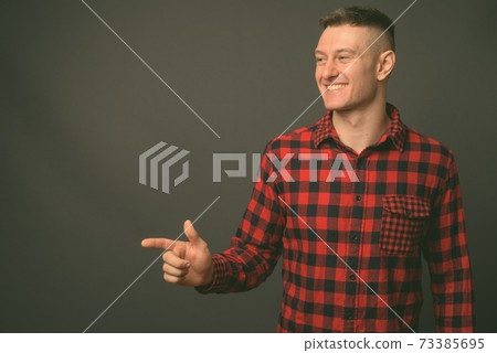 Studio shot of young handsome man against gray background Studio shot of young handsome man against gray background 73385695