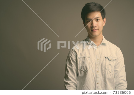 Young handsome Asian businessman wearing white shirt against gray background 73386006