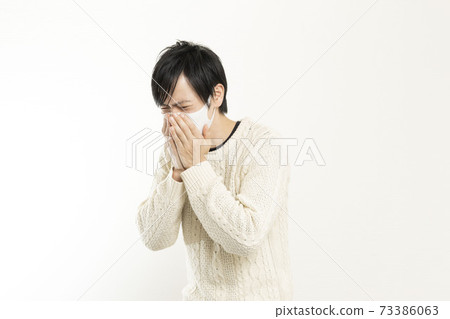 A man in a mask / holding his head with a headache / a single man who is sick / 73386063