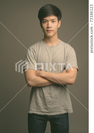 Young handsome Asian man against gray background Young handsome Asian man against gray background 73386123