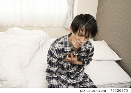 A man in pajamas who can't get heartburn in the morning because yesterday's drinking party continued until late 73386370