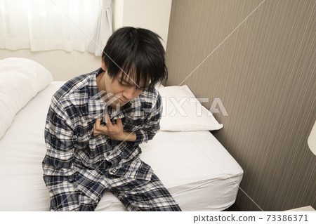 A man in pajamas who can't get heartburn in the morning because yesterday's drinking party continued until late 73386371