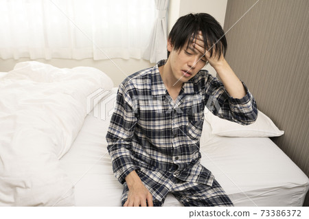 一個穿著睡衣的男人,醒來時感到發燒,感到噁心,無法上班 一個穿著睡衣的男人,醒來時感到發燒,感到噁心,無法上班 73386372