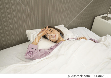 A woman sleeping sick / a woman sick / a beautiful woman sleeping in bed 73386399