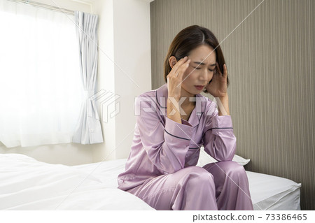 一個女人生病了/一個女人生病/一個美麗的女人在床上睡覺/一個美麗的女人坐在床上 73386465