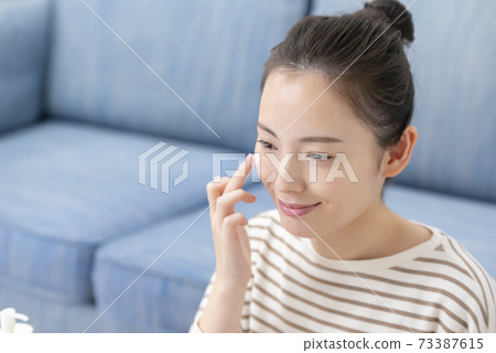 Beauty image Young woman applying cream 73387615