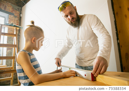 Young family doing apartment repair together themselves. Happy father and son doing home makeover or renovation 73388334