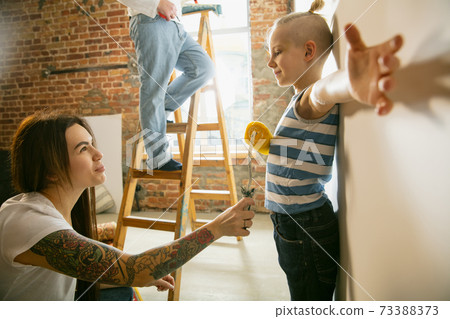 Young family doing apartment repair together themselves. Mother, father and son doing home makeover or renovation Young family doing apartment repair together themselves. Mother, father and son doing home makeover or renovation 73388373