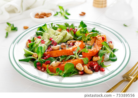 Fresh vegetable salad with lambs lettuce, baked butternut squash or pumpkin, avocado, pomegranate, cashew and almond nuts. Healthy vegetarian food concept. 73389556