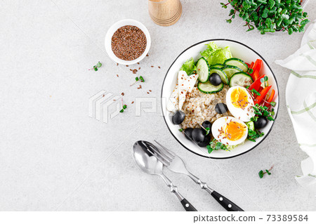 Greek inspired savory oatmeal with fresh cucumber, bell pepper, olives, lettuce, feta cheese, radish sprouts and soft-boiled egg for healthy breakfast, top view Greek inspired savory oatmeal with fresh cucumber, bell pepper, olives, lettuce, feta cheese, radish sprouts and soft-boiled egg for healthy breakfast, top view 73389584