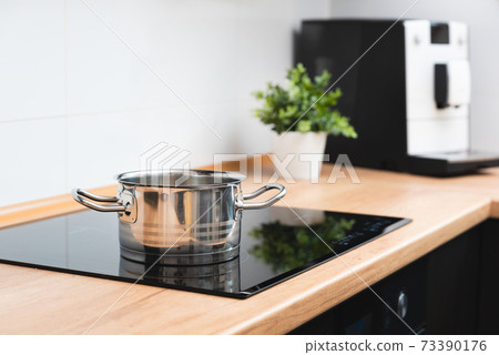 Pot in the kitchen on the induction hob 73390176