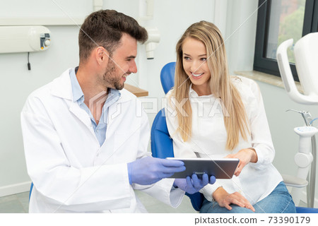 Dentist showing teeth x-ray on tablet screen Dentist showing teeth x-ray on tablet screen 73390179