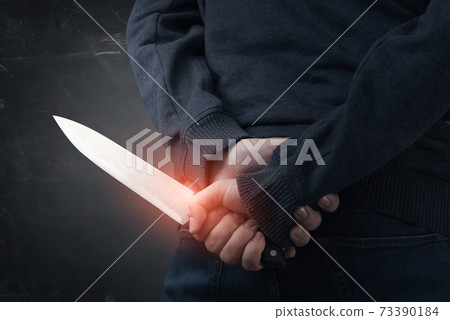 Murderer holding knife in his hand 73390184
