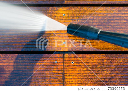 cleaning terrace with a power washer - high water pressure cleaner on wooden terrace surface 73390253