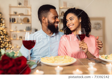Happy black woman and man drinking wine and having dinner 73392142