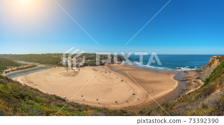 Delightful panoramic view of the Portuguese beach of the village of Odeceixe with tourists in summer. Delightful panoramic view of the Portuguese beach of the village of Odeceixe with tourists in summer. 73392390