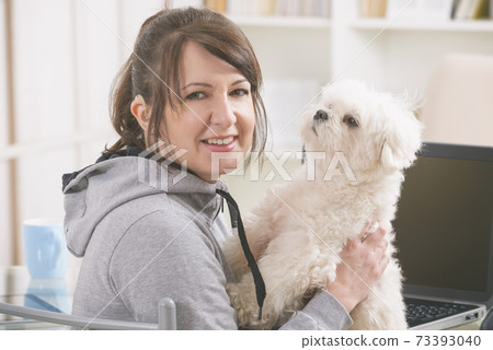 Hearing impaired woman with her dog at home office Hearing impaired woman with her dog at home office 73393040