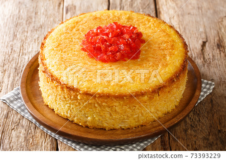 Spiced Chicken Tahchin is a Persian crispy edged rice cake casserole dish consisting of primarily rice, yogurt, eggs, and saffron closeup in the plate. Horizontal 73393229