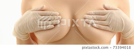 Naked woman examining her bust with hands 73394018