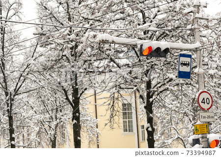 A working traffic light on a city street in winter.The red light of the traffic light is on 73394987