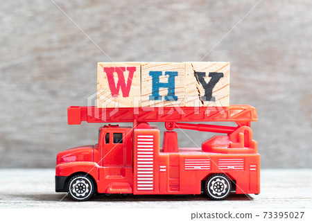 Red fire truck hold letter block why in word  on wood background 73395027