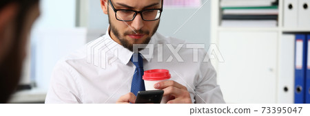 Businessman holding in arms cup of coffee and cell phone 73395047