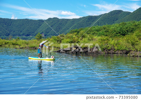 男人和狗在夏天享受站立式槳在湖上沖浪 男人和狗在夏天享受站立式槳在湖上沖浪 73395080
