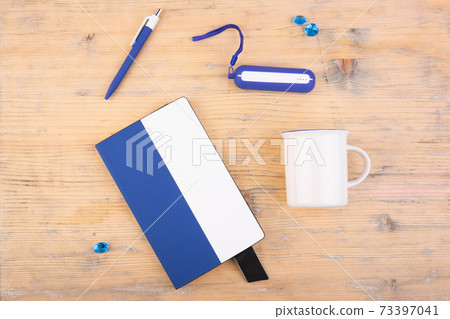 Blue handle and white notebook with white cup and charger 73397041