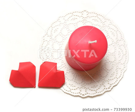 Single thick pink aromatic candle on white openwork paper napkin and couple 3D handmade paper hearts on white background top closeup view isolated. Love, rendezvous, relations, date, dating concept Single thick pink aromatic candle on white openwork paper napkin and couple 3D handmade paper hearts on white background top closeup view isolated. Love, rendezvous, relations, date, dating concept 73399930