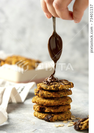 Oat cookies. Female hand pouring chocolate on homemade cookies. Oat cookies. Female hand pouring chocolate on homemade cookies. 73401137