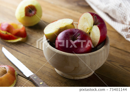 Red apples slices in a bowl on wooden rustic table. 73401144