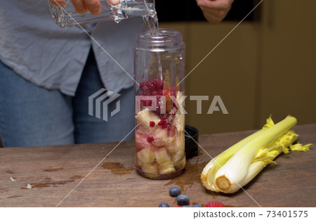 Woman pouring water in blender glass 73401575