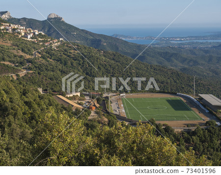 Aerial View of green soccer field at Baunei village in beautiful landscape of Supramonte mountains with with limestone rocks, Arbatax penisula, mediterranean sea and lush vegetation. Sardinia, Italy 73401596
