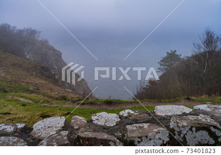 A view over the ocean from a steep hill a misty day. Picture from Kullen nature reserve, Scania, Sweden A view over the ocean from a steep hill a misty day. Picture from Kullen nature reserve, Scania, Sweden 73401823