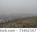 River bank on a foggy winter evening 73402167