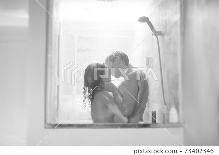 black-white. soft focus. man and woman take shower shooting through window. 73402346