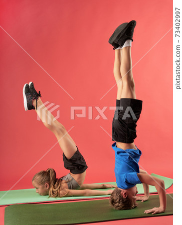 Adorable kids practicing yoga against red background 73402997