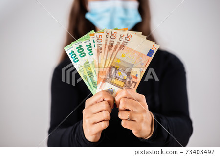 Hands holding euro cash during coronavirus pandemic. 73403492