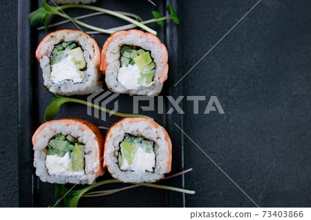 Sushi rolls with grilled salmon on black plate 73403866