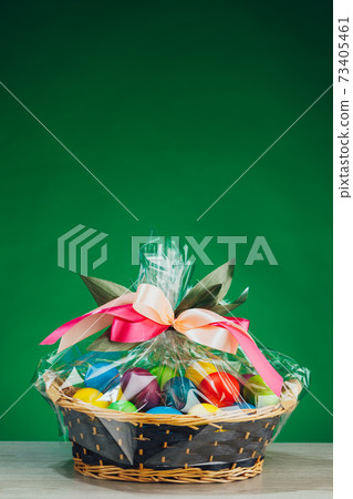 Easter gift basket with multicolor eggs, green background Easter gift basket with multicolor eggs, green background 73405461