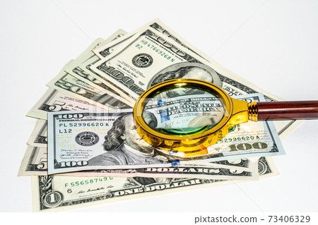 Magnifier lies on American dollars isolated on white background 73406329