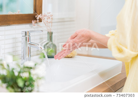 Hands of a woman washing her hands in the washbasin of a house Hands of a woman washing her hands in the washbasin of a house 73407303