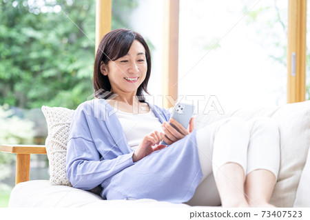 在客廳裡操作智能手機的中年女人 73407523