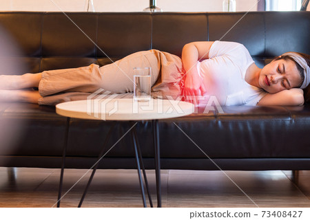 Depress woman having painful stomach ache,Female suffering from abdominal pain,Period cramps or premenstrual syndrome lying on sofa Depress woman having painful stomach ache,Female suffering from abdominal pain,Period cramps or premenstrual syndrome lying on sofa 73408427