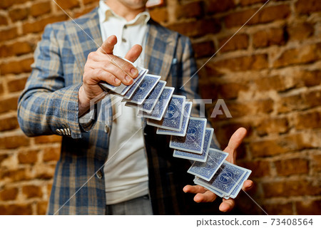 Magician throws a continuous stack of cards from hand to hand Magician throws a continuous stack of cards from hand to hand 73408564