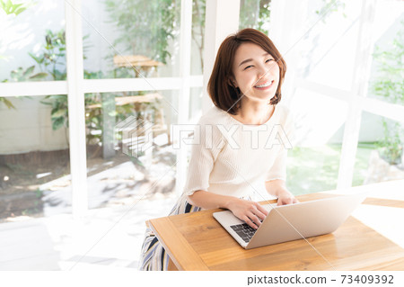 觀看一台便攜式計算機的婦女在屋子裡 73409392