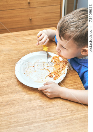 Lovely kid with large eyes eats sloppy delicious pasta Lovely kid with large eyes eats sloppy delicious pasta 73409638