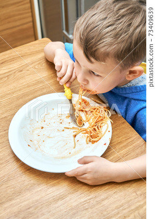 Lovely kid with large eyes eats sloppy delicious pasta Lovely kid with large eyes eats sloppy delicious pasta 73409639