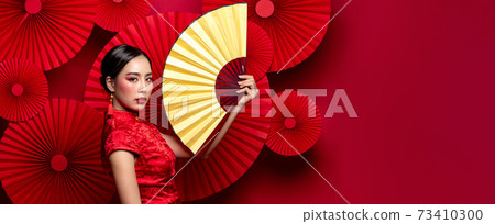 Beautiful glamour Asian woman in traditional Chinese dress holding golden fan Beautiful glamour Asian woman in traditional Chinese dress holding golden fan 73410300