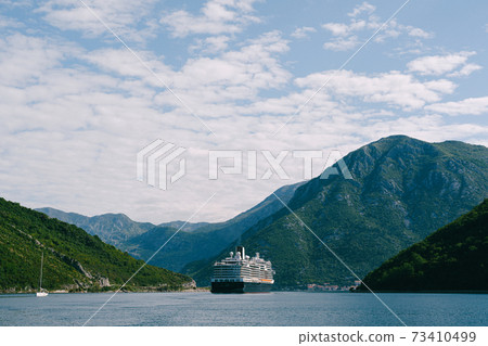 A tall, high-rise huge cruise liner in the Verige Strait, in the Boka Kottorska - Kotor Bay in Montenegro, against the backdrop of the city of Perast. A tall, high-rise huge cruise liner in the Verige Strait, in the Boka Kottorska - Kotor Bay in Montenegro, against the backdrop of the city of Perast. 73410499